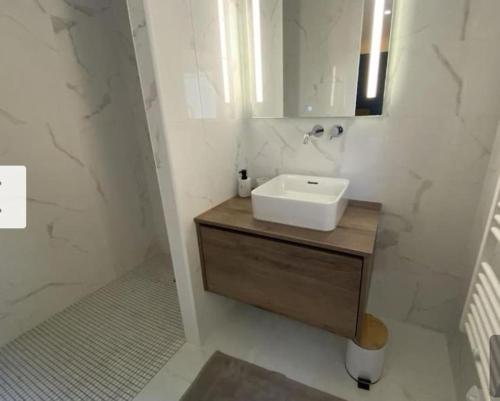 une salle de bain avec un lavabo et un miroir dans l'établissement Appartement vue mer piscine, à La Teste-de-Buch