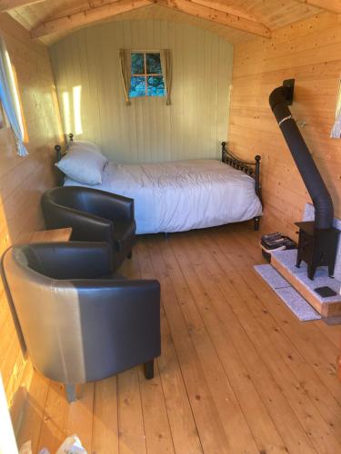 ein Schlafzimmer mit einem Bett und einem Stuhl in einer Hütte in der Unterkunft Shepherds Hut on Alpaca and working farm in Blaenau-Ffestiniog