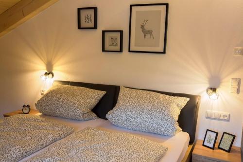 a bed with two pillows and pictures on the wall at Ferienwohnung Bergspitz in Grainau