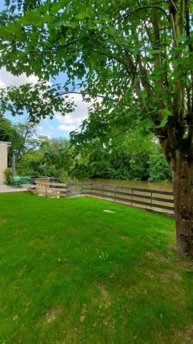un champ verdoyant avec un arbre et une clôture dans l'établissement River house with 3 bedrooms, à Montigny-sur-Loing