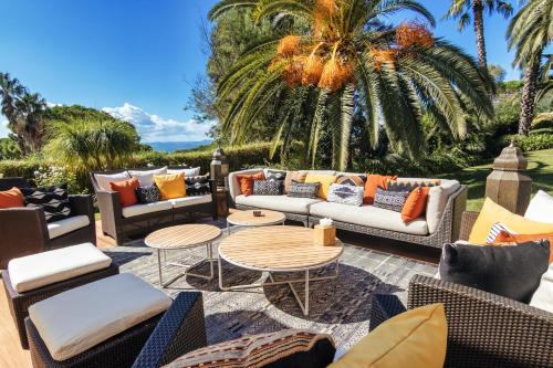 d'une terrasse avec des canapés, des tables et des palmiers. dans l'établissement Villa Hollywood Luxe, à Saint-Tropez