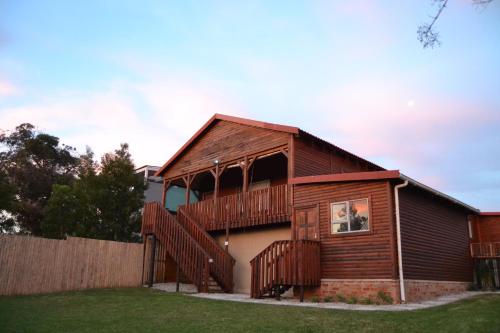a wooden house with a deck and a fence at The Wooden House in Plettenberg Bay