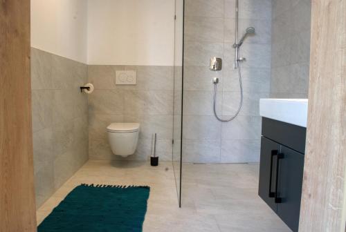 a bathroom with a shower and a green rug at myQuartier City Chalets in Innsbruck
