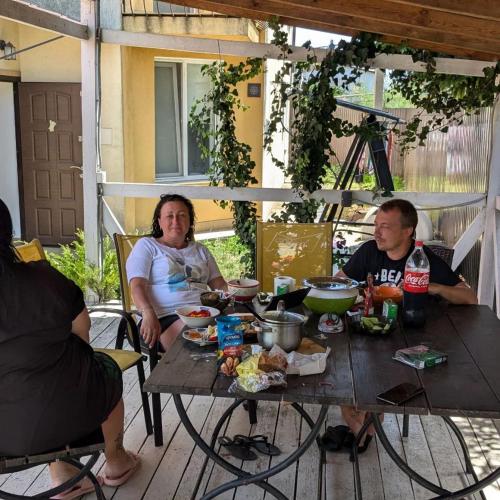 a group of people sitting around a wooden table at Guest House Dacha in Karolino-Buhaz