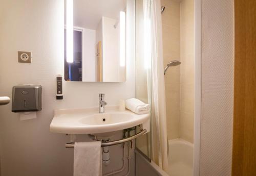 a white bathroom with a sink and a shower at B&B HOTEL Avignon 1 in Le Pontet