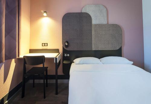 a bedroom with a bed and a table and a chair at B&B HOTEL Avignon 1 in Le Pontet