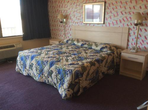a bedroom with a bed with a comforter on it at MacThrift Motor Inn in Virginia Beach