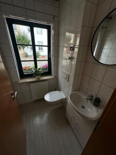 un bagno con lavandino, WC e finestra di Ferienwohnung MONI a Penkun