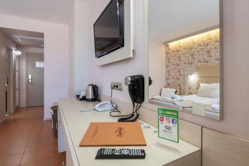 a room with a desk with a phone and a bed at Aphrodite Beach Hotel in Nesebar