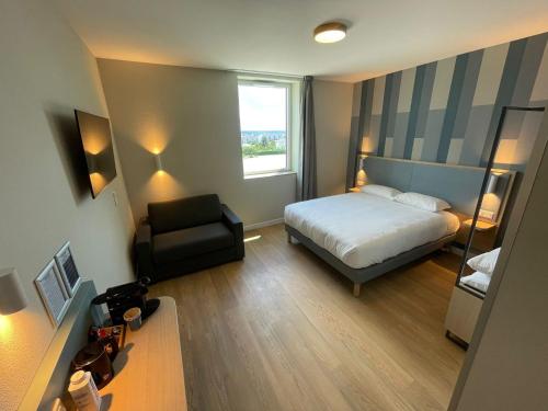 a bedroom with a bed and a chair and a window at Kyriad Limoges - Ester in Limoges