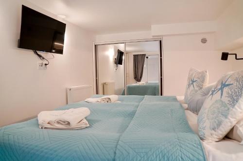 a bedroom with a blue bed with towels on it at Chrobry by Baltic Home in Międzyzdroje