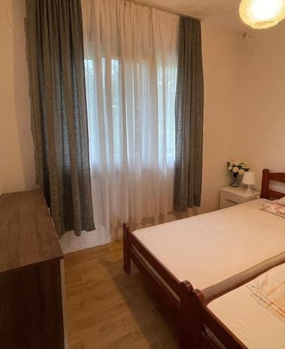 a bedroom with a bed and a window with curtains at Idylle in der Natur mit Burgblick in Sutomore