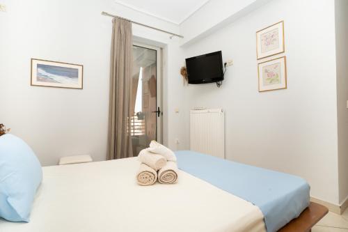 a bedroom with a white bed with towels on it at Maria's Airport Apartment, 4' metro, 10' airport, 15' beach, 40' city center in Koropíon