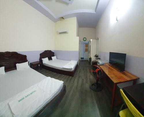 a room with two beds and a desk with a computer at Khách Sạn Ngọc Hân in Tinh Bien