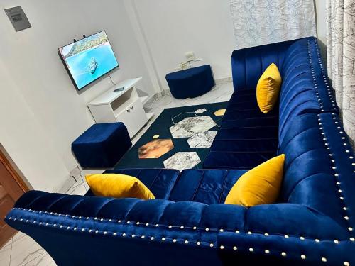 ナイロビにあるStelvic One Bedroom Airbnbの青いソファ(黄色の枕付)が備わるリビングルーム