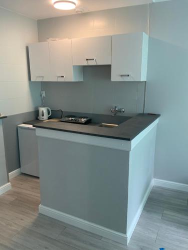 a kitchen with white cabinets and a counter top at Apartamencik Konopnickiej 2 in Dziwnów