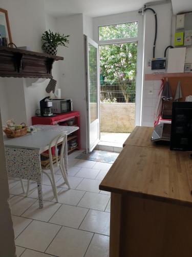 une cuisine avec une table et une porte donnant sur une cour dans l'établissement La Demeure, à Gabarret