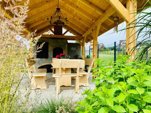 a wooden pergola with a table and a fireplace at Osada Snozka in Kluszkowce
