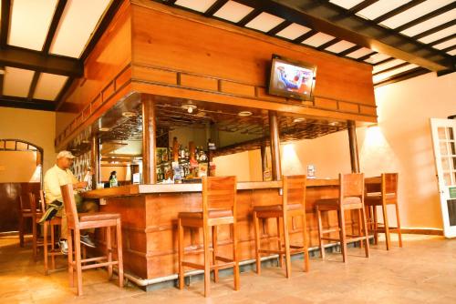 ein Mann steht an einer Bar mit Holzstühlen in der Unterkunft Wagon Wheel Hotel Eldoret in Eldoret