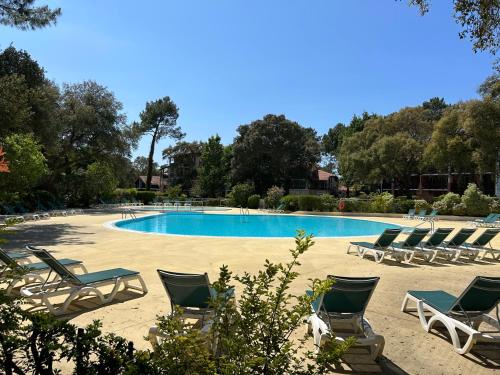 un groupe de chaises longues et une piscine dans l'établissement T2 près de la plage et du Club House du Golf, à Moliets-et-Maa