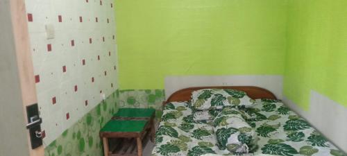 a small bedroom with a bed and a green wall at Javalindra Homestay Tour and Travel in Banyuwangi