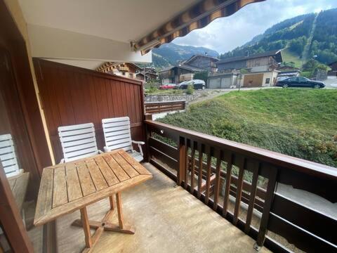 d'un balcon avec une table en bois et deux chaises blanches. dans l'établissement Areches Village, à Arêches