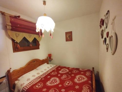 - une chambre avec un lit rouge et un lustre dans l'établissement Areches Village, à Arêches
