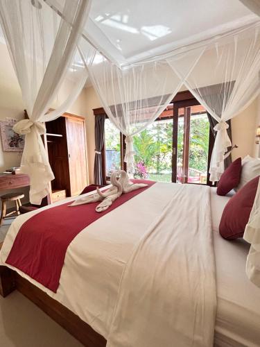 a bedroom with a large white bed with curtains at Canting Bali Suite in Ubud