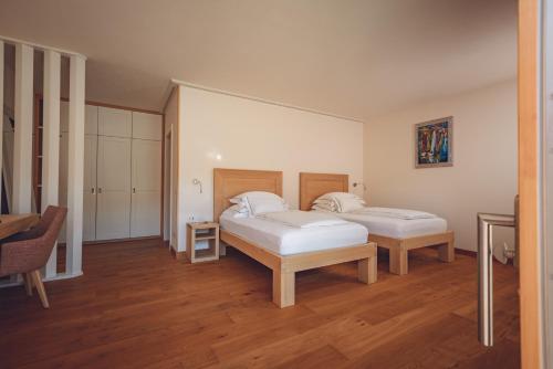 two beds in a room with wooden floors at Agriturismo La Pertica in Costermano sul Garda