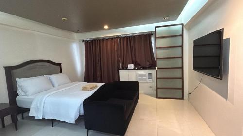 a bedroom with a bed with a chair and a book shelf at H&M One Palmtree Villas in Manila