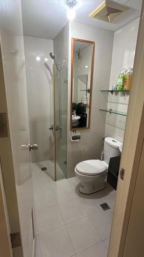 a bathroom with a toilet and a glass shower at H&M One Palmtree Villas in Manila