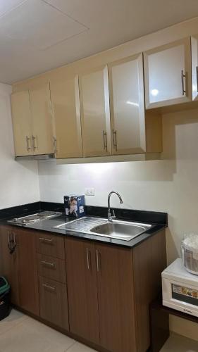 a kitchen with wooden cabinets and a sink at H&M One Palmtree Villas in Manila