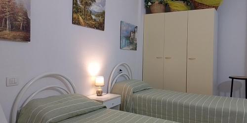 a bedroom with two beds and a lamp on a table at Casa Marconi in San Teodoro