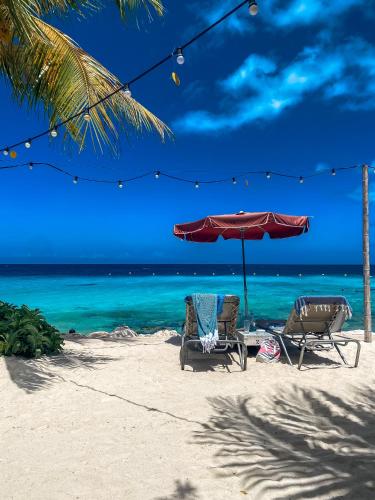 two chairs and an umbrella on the beach at Luxe zeezicht appartement Bayside, Jan Thiel Boca Gentil in Willemstad