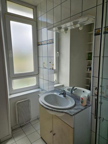 La salle de bains est pourvue d'un lavabo, d'une fenêtre et d'une baignoire. dans l'établissement Un calme près de l'eau, à Lanvéoc