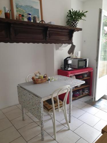 - une table et des chaises dans la cuisine équipée d'un four micro-ondes dans l'établissement La Demeure, à Gabarret