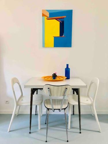 une table et des chaises avec un tableau mural dans l'établissement STUDIO, 11, parc de Belleville, à Paris