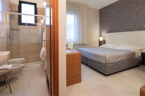 a bedroom with a bed and a bathroom with a shower at Astra Hotel in Ferrara