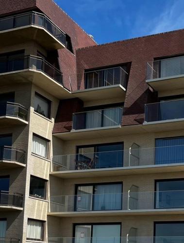 an apartment building with balconies and a red roof at Premium Holidays - Stylish appartement Villa Castelli with C-View at Nieuwpoort! in Oostduinkerke