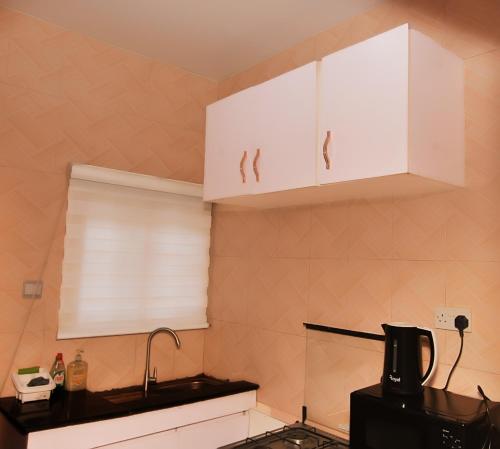 a kitchen with white cabinets and a sink at Haven Heights Apartments in Lagos