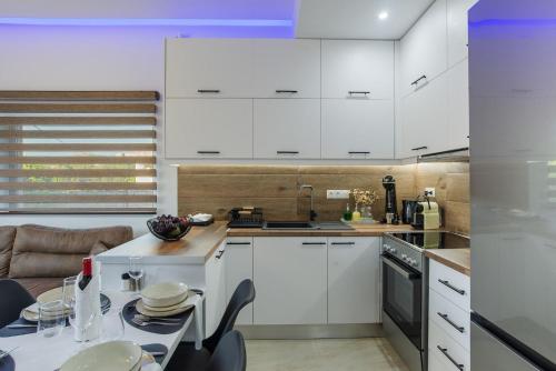 a kitchen with white cabinets and a table with chairs at Casa Manou - Kalyves beach in Kalyves