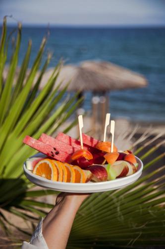 a person holding a plate of fruit on a beach at Akti Hotel Kavala in Paleo Tsifliki