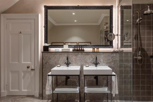 a bathroom with two sinks and a mirror at SCHLOSS Roxburghe, part of Destination by Hyatt in Kelso