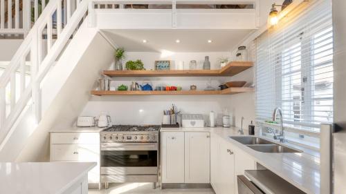 a kitchen with white cabinets and a sink at Bliss on the Bay in Struisbaai