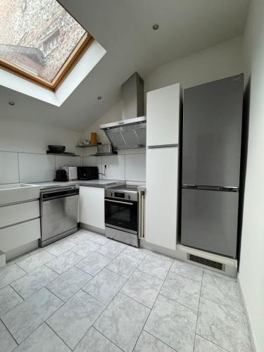 d'une cuisine équipée d'appareils en acier inoxydable et d'une fenêtre. dans l'établissement Maison de ville proche du port au cœur du Carré des Arts de Honfleur, à Honfleur