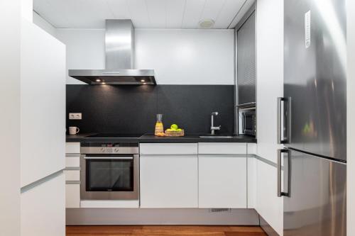 a kitchen with white cabinets and a stainless steel refrigerator at Aspasios Paseo de Gracia Apartments in Barcelona