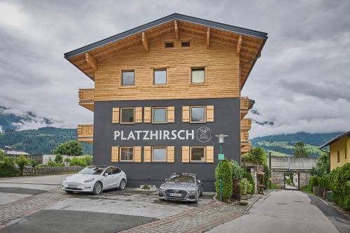 a building with two cars parked in front of it at Platzhirsch Rooms - B&B - SELF CHECK-IN in Piesendorf