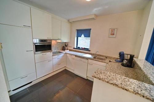a large kitchen with white cabinets and a window at Résidence Durbuy in Durbuy