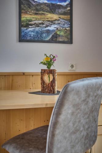 a desk with a chair and a vase with flowers at Platzhirsch Rooms - B&B - SELF CHECK-IN in Piesendorf