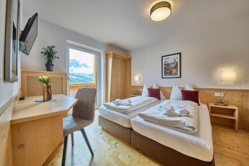 a hotel room with a bed and a desk at Platzhirsch Rooms - B&B - SELF CHECK-IN in Piesendorf
